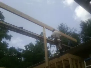 Carpenter setting a ridge beam over a new addition frame — Ice Dam Removal by Roofing Brothers in Wharton