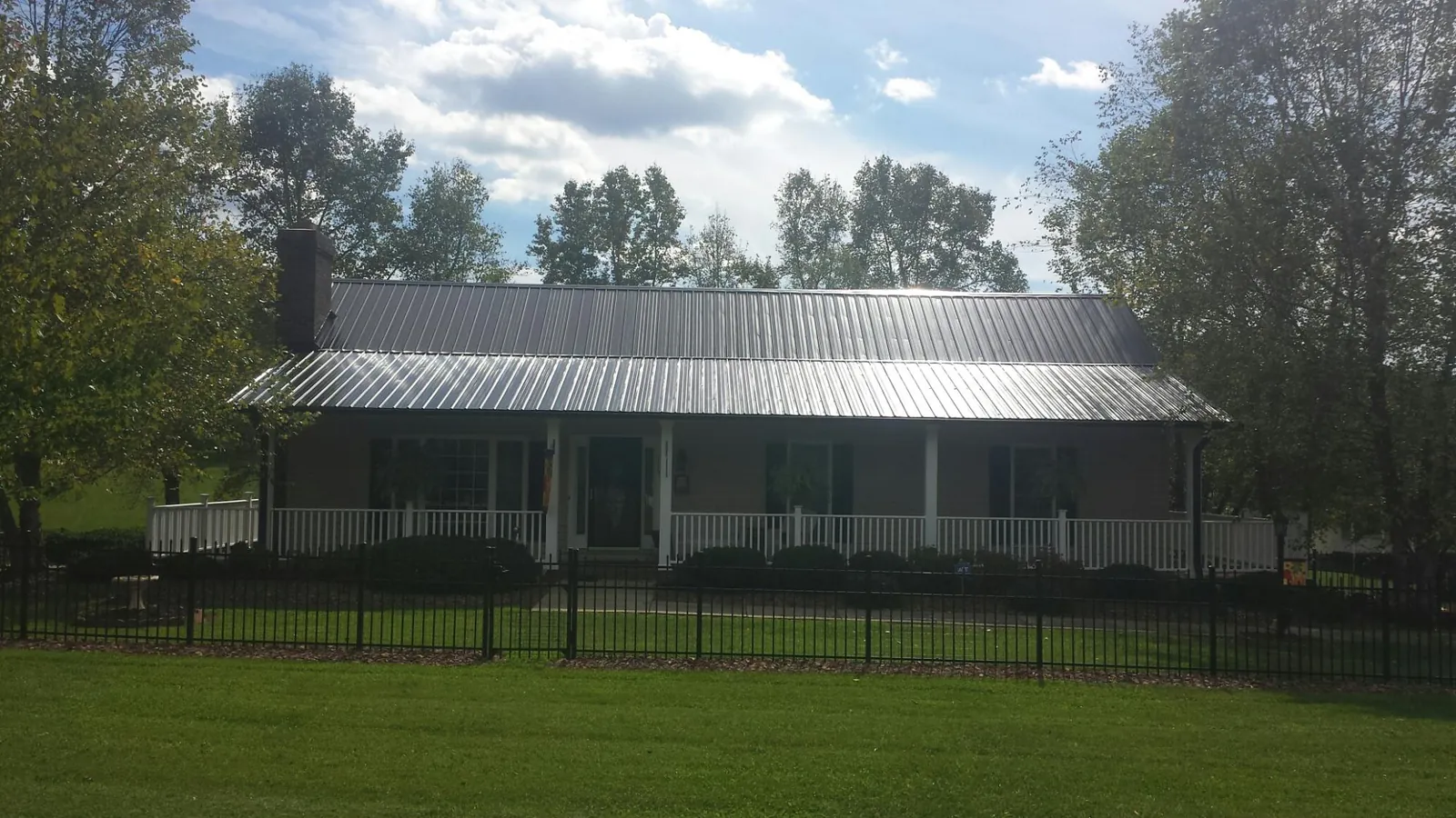 Gray metal roof on a brick ranch with a full width front porch — Gutter Guard Installation work by our crew in Wharton