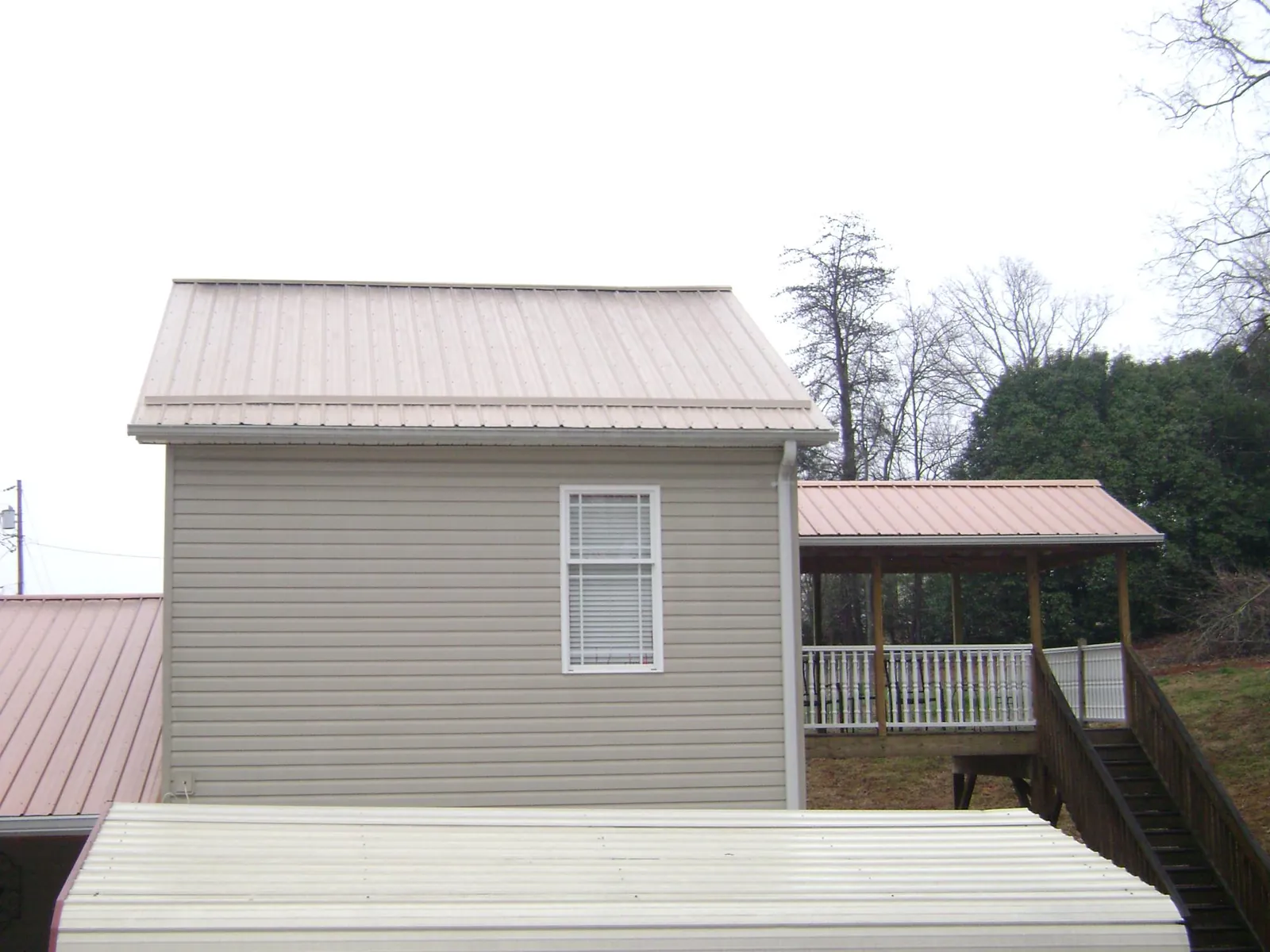 Tan metal roofs on a two story addition and attached porch, from a Roof Replacement job in Wharton